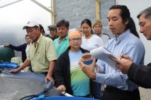 Daniel Nguyen explains the aquaponics process to members of the Vietnamese community.  Photo Credit: David T. Baker