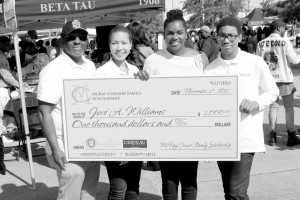 Xavier alumnus Karl Connor (left) awards a homecoming weekend scholarship to current student Jere Williams (center right), a senior, on Nov. 17