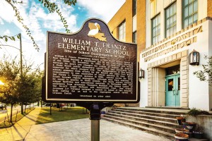 A historical placard stands in front of William T. Frantz Elementary School commemorating that school's place in American history when six year old Ruby Bridges became the first Black to desegregate the all-white school in 1960. The site is now home to Akili Academy, a charter school. A statue of Ruby stands in the school's courtyard, while the classroom she was assigned to has been restored to the way it would have looked when she attended the school.