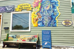 A mural from one of the 2021 Mardi Gras "house floats" captures the Backstreet Cultural Museum's founder, the late Sylvester Francis. Nearby is a bench donated by Hanks' Bar. Photo by Keith Hill